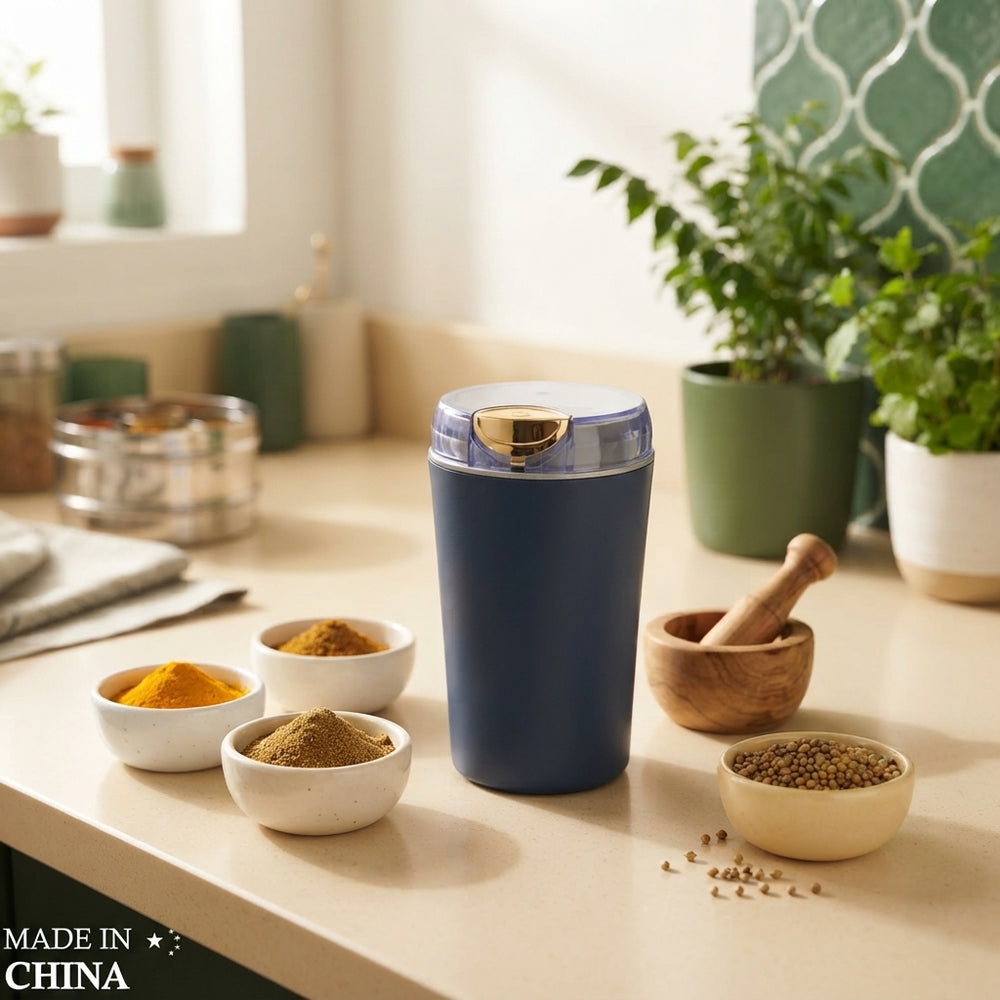 A compact electric mini grinder on a kitchen counter next to bowls of ground spices in a modern home.